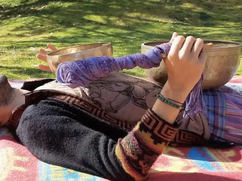 Campane tibetane accanto a una persona distesa durante un bagno sonoro all'aperto