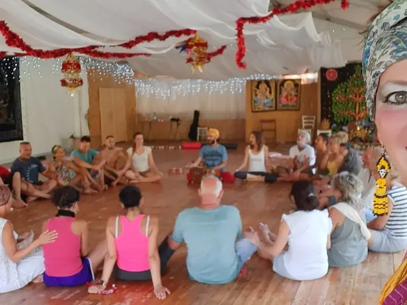 Gruppo seduto in cerchio sotto una tenda durante una meditazione collettiva